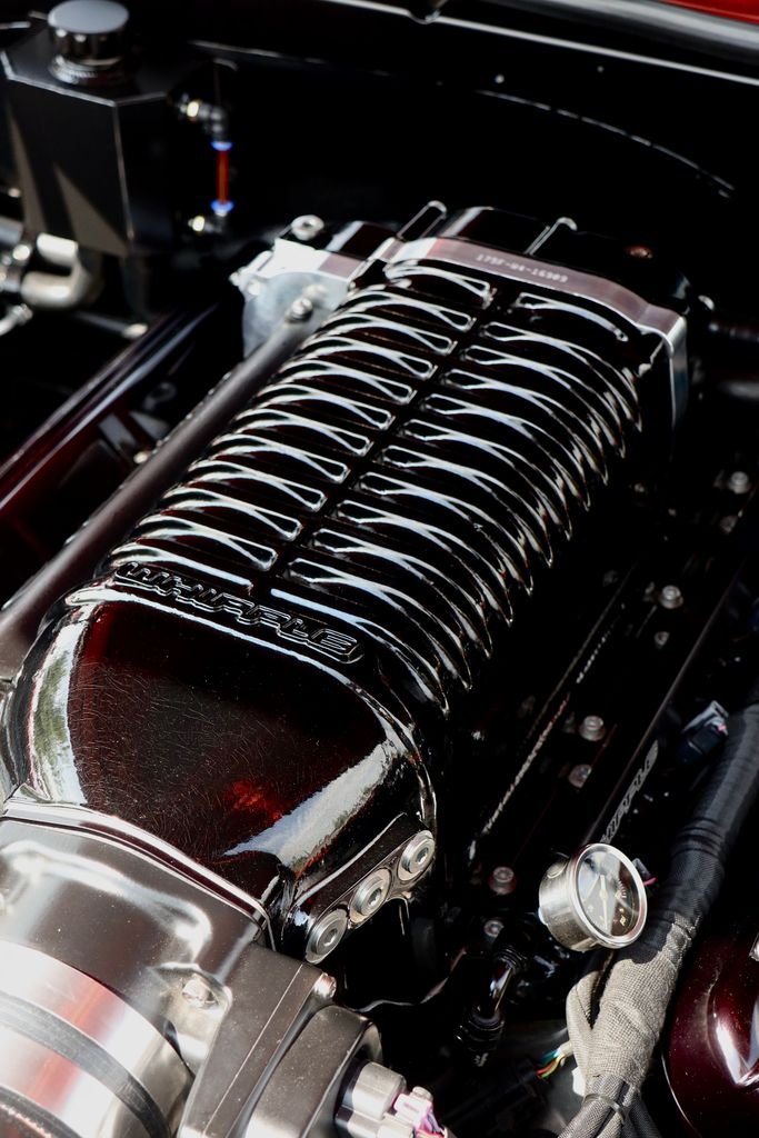 Detailed view of a polished car engine showcasing a supercharger under bright lighting.
